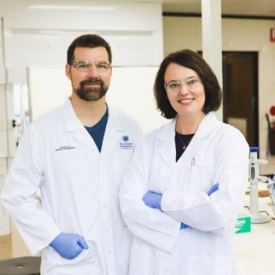 Two scientists in a lab wearing white lab coats 